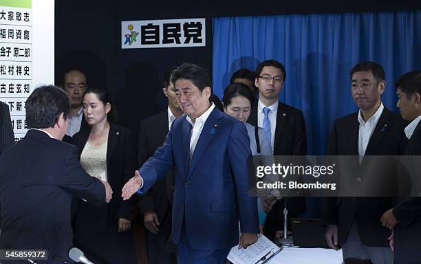 Shinzo Abe, Japan's prime minister and president of the Liberal Democratic Party , center, shakes hands with a party executive as he arrives at a...