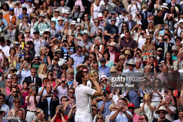 Andy Murray of Great Britain kisses the trophy following victory in the Men's Singles Final against Milos Raonic of Canada on day thirteen of the...
