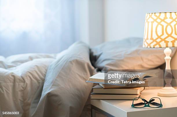 usa, new jersey, bed with lamp, books and glasses on bedside table - night table stock pictures, royalty-free photos & images