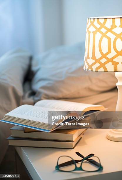usa, new jersey, bed with lamp, books and glasses on bedside table - bedside table stock pictures, royalty-free photos & images