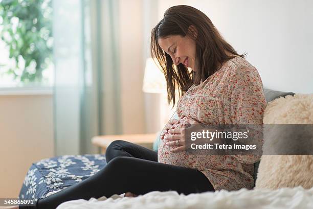 usa, new jersey, pregnant woman sitting on bed - woman smiling facing down stock pictures, royalty-free photos & images