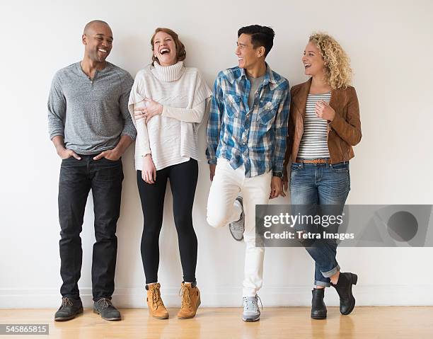 usa, new jersey, laughing friends standing against white wall - group arm in arm stock pictures, royalty-free photos & images