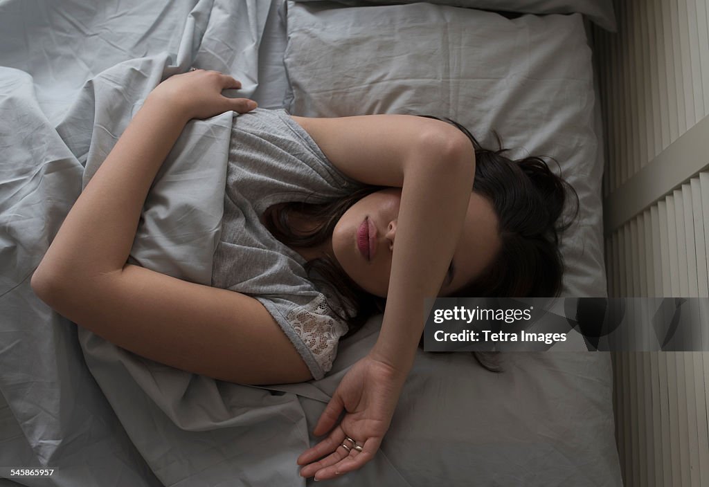 USA, New Jersey, Elevated view of young woman sleeping in bed
