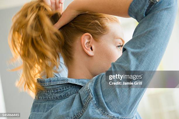 usa, new jersey, young woman tying hair - ponytail hair stock pictures, royalty-free photos & images