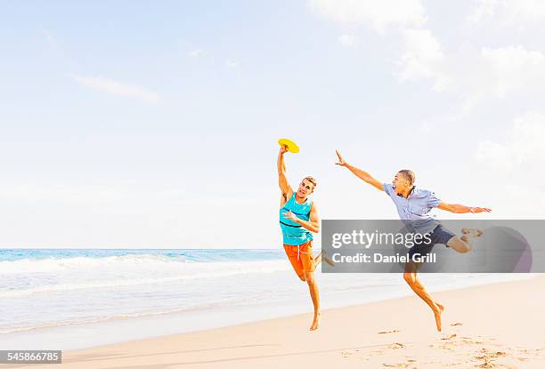 usa, florida, jupiter, young men playing plastic disc on beach - frisbee fotografías e imágenes de stock