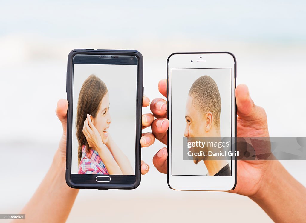 USA, Florida, Jupiter, Hands holding smart phones with pictures of young people