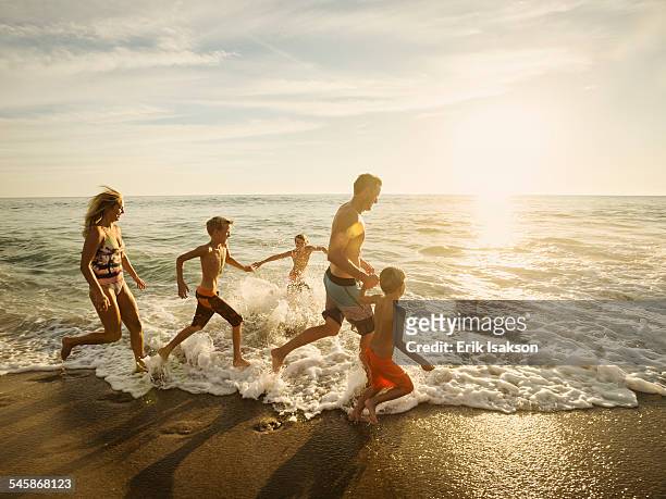 usa, california, laguna beach, family with three children (6-7, 10-11, 14-15) running on beach - beach holiday stock pictures, royalty-free photos & images