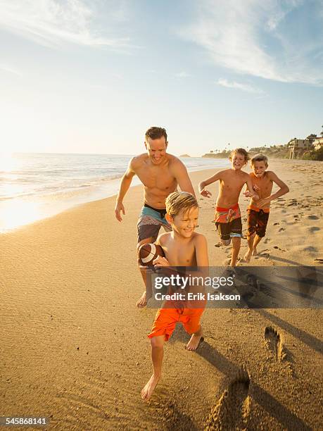 usa, california, laguna beach, father playing football on beach with his three sons (6-7, 10-11, 14-15) - laguna beach california stock pictures, royalty-free photos & images