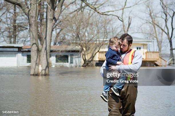 usa, illinois, man with son wading in floodwaters - flood rescue stock pictures, royalty-free photos & images