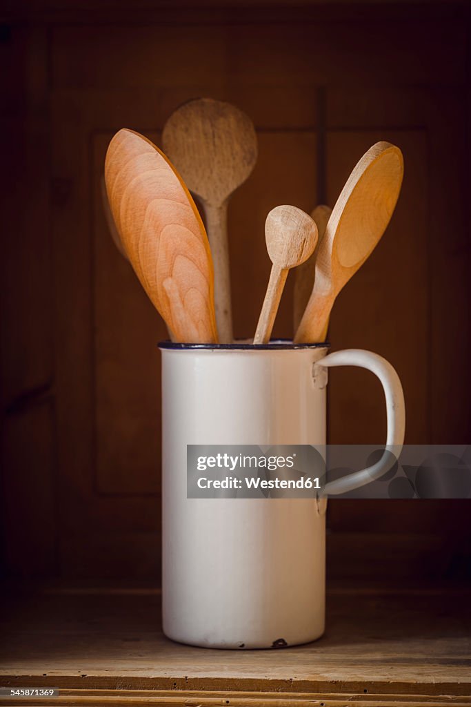 Wood spoons in pot on wooden shelf