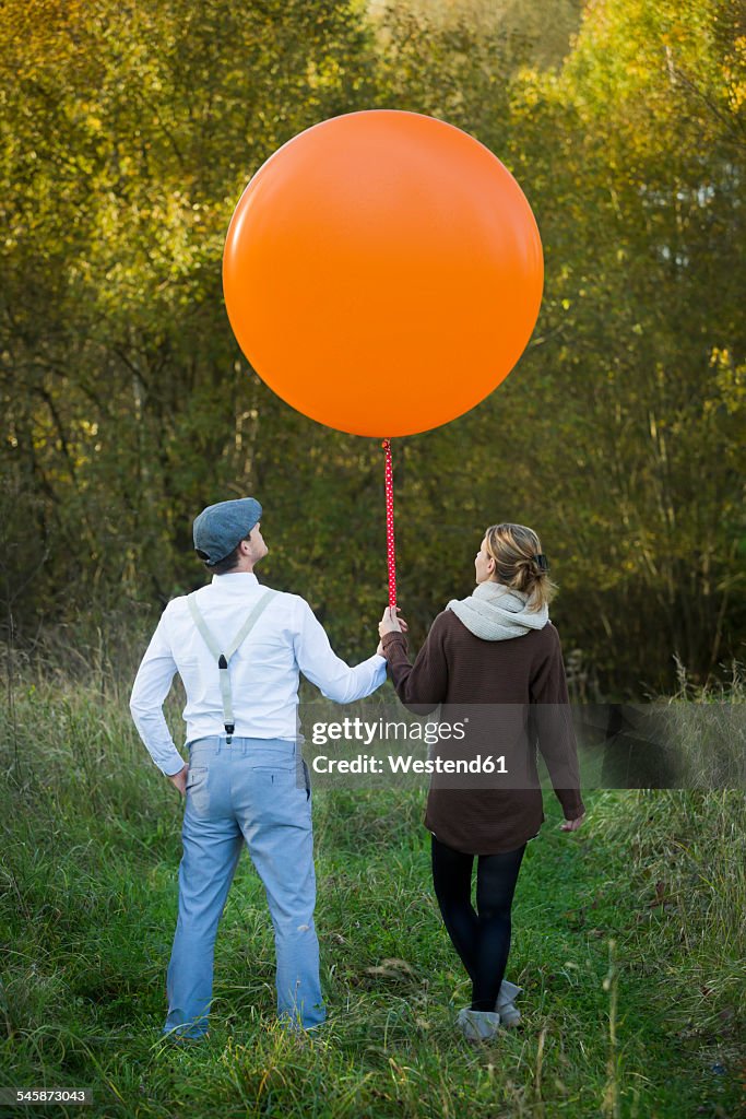 Couple standing with balloon on meadow