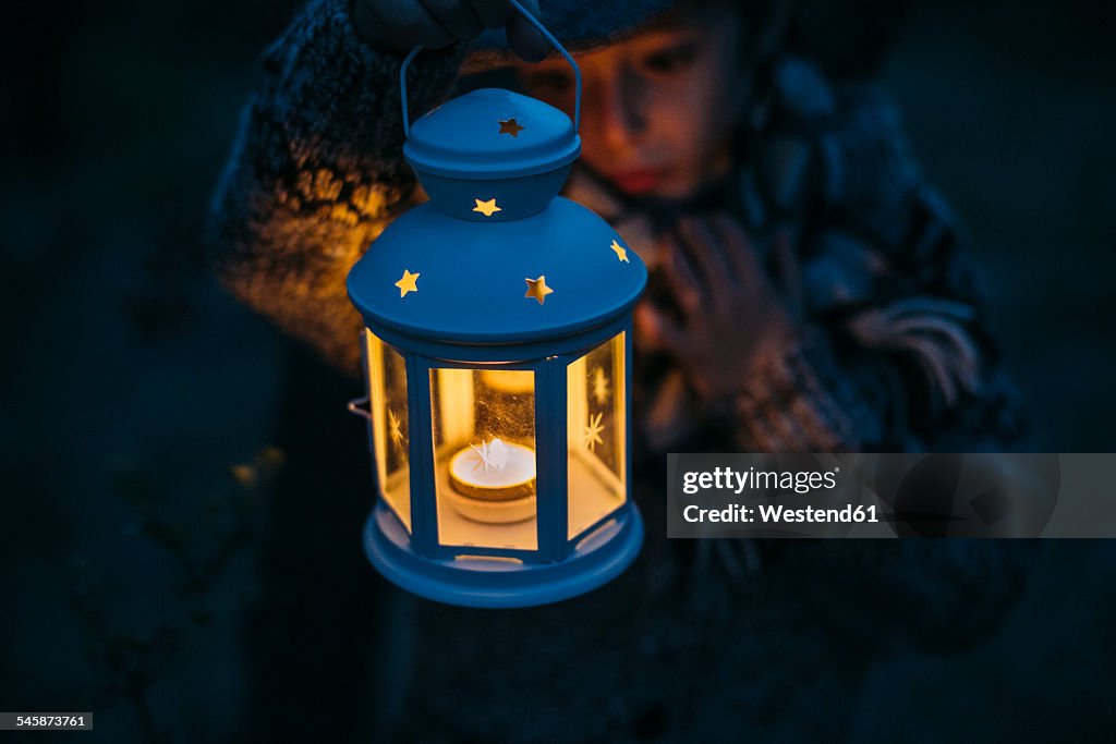 Italy, Grosseto, boy looking at a lighted Christmas lantern by night