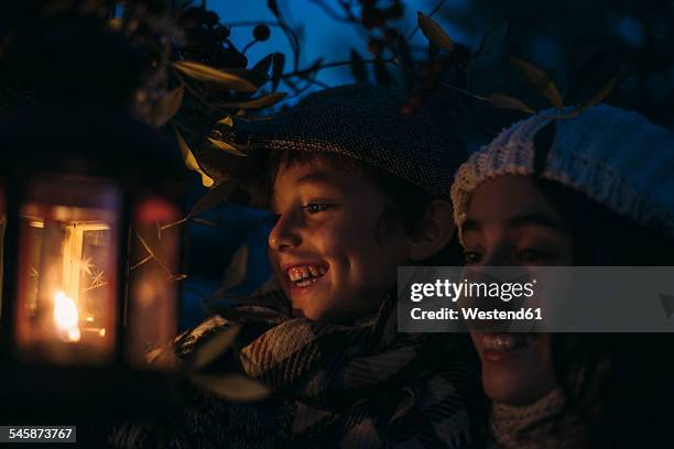 italy, grosseto, laughing siblings with lighted christmas lantern by night - kaarslicht stockfoto's en -beelden