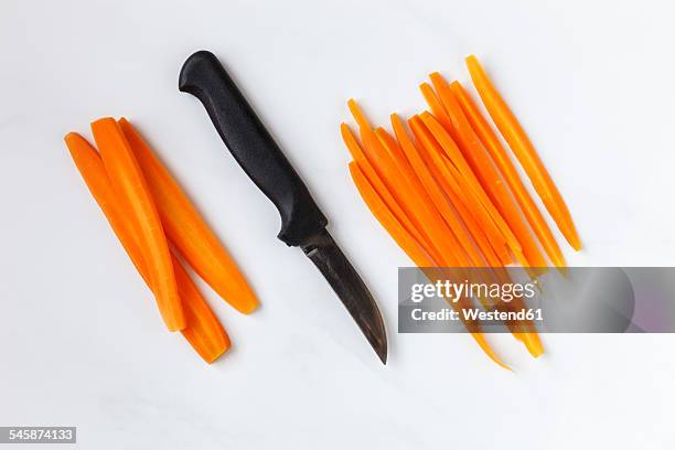 whole and sliced carrots and kitchen knife on white ground - tagliato a pezzi foto e immagini stock