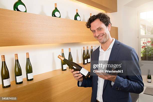 man in shop holding bottle of wine - volkach stock pictures, royalty-free photos & images