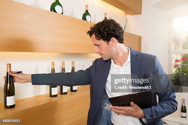 man in shop checking bottle of wine - volkach stock pictures, royalty-free photos & images