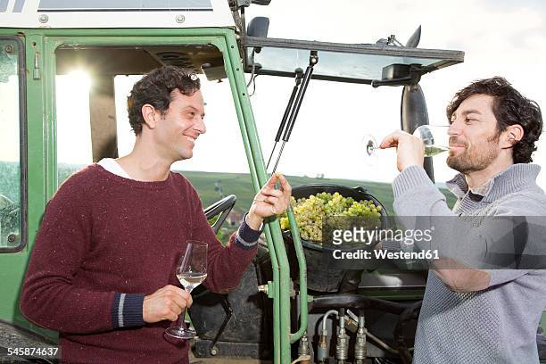 germany, bavaria, volkach, two winegrowers tasting white wine at tractor - volkach stock pictures, royalty-free photos & images