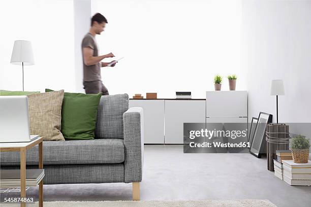 young man using digital tablet in his living room - man living room stockfoto's en -beelden