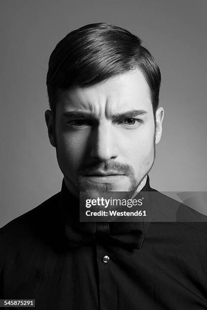 portrait of serious looking man wearing black bow and black shirt - annoyed face brunnette stock-fotos und bilder