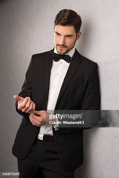 portrait of man wearing dinner jacket and bow leaning at wall - esmoquin fotografías e imágenes de stock