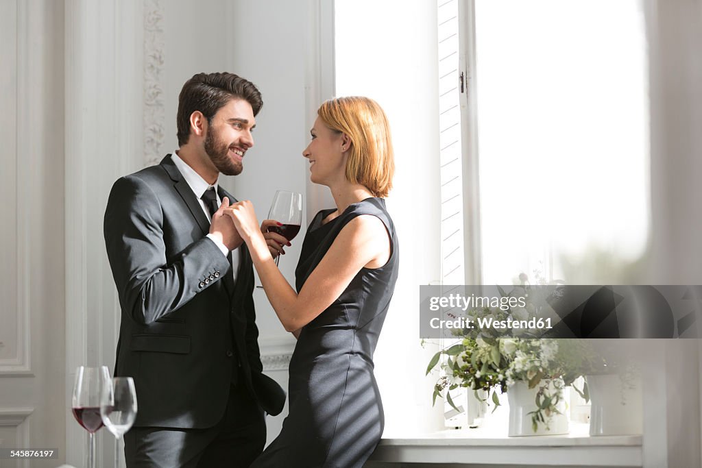 Elegant couple with red wine glasses in restaurant