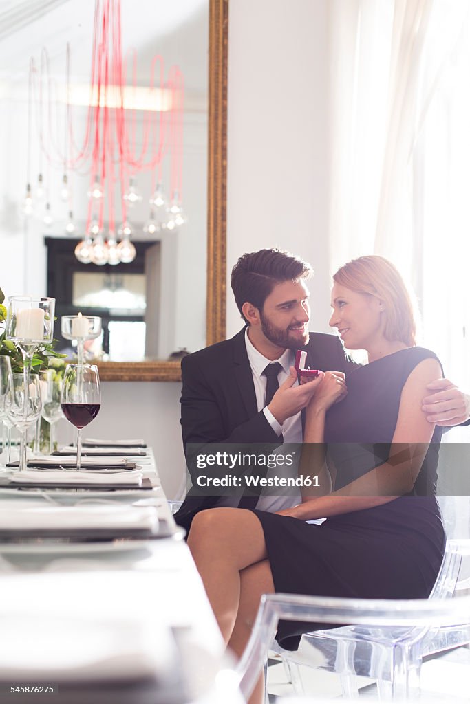 Elegant couple with engagement ring in restaurant