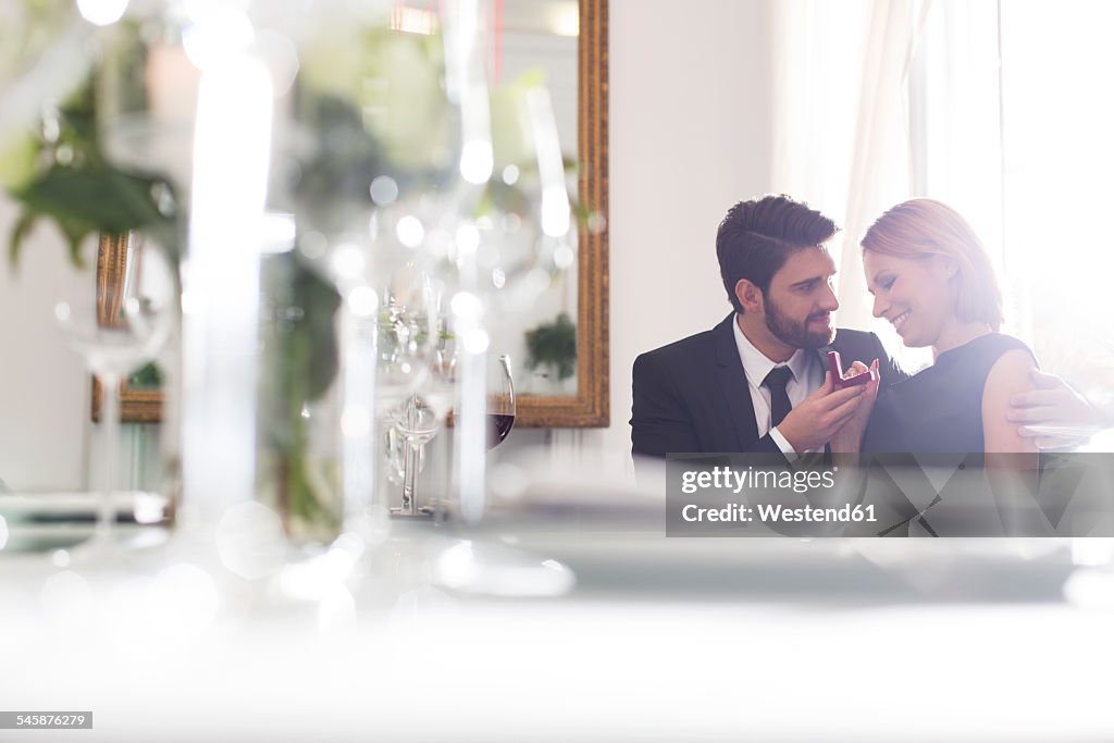 Elegant couple with engagement ring in restaurant