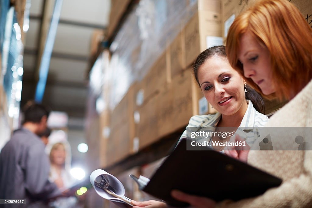 Two women with clipboard in warehouse
