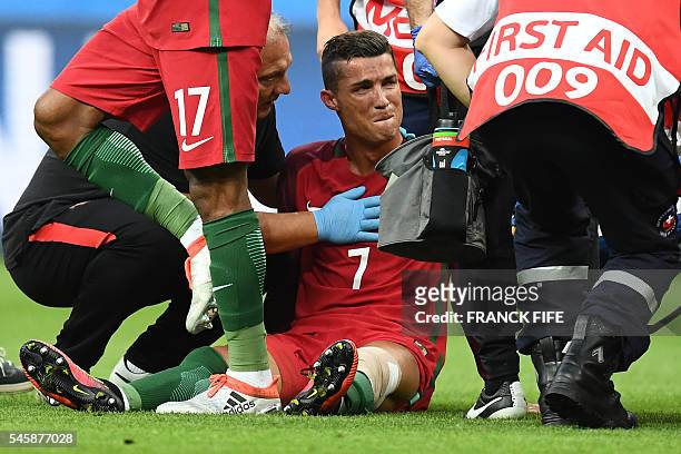 Portugal's forward Cristiano Ronaldo reacts as medics arrive on the pitch during the Euro 2016 final football match between France and Portugal at...