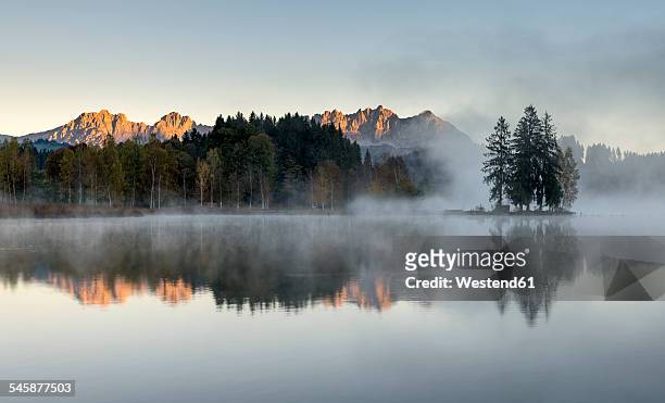 austria, tyrol, kitzbuehl, view to schwarzsee with morning mist and kitzbuehel alps in the background - kitzbuhel stock pictures, royalty-free photos & images