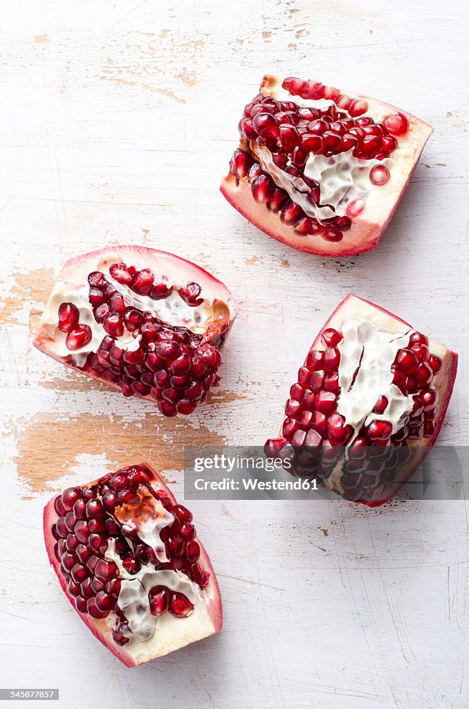 Four pieces of pomegranates on white wood