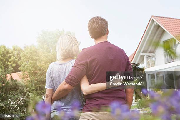 rear view of mature couple in garden - mittelstand stock-fotos und bilder