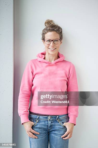 portrait of smiling mature woman wearing pink hooded jacket - blonde glasses stock-fotos und bilder