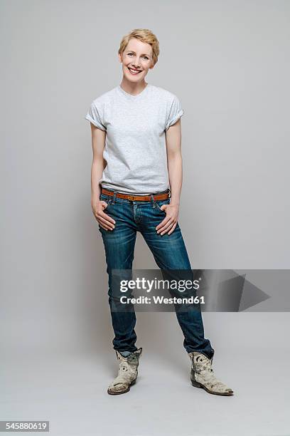 relaxed woman with hands in her pockets standing in front of grey background - white t shirt studio stock pictures, royalty-free photos & images