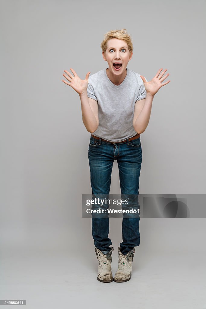 Excited woman standing in front of grey background