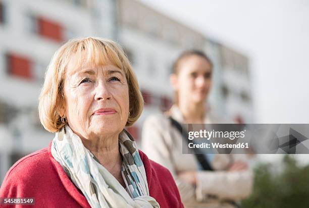 portrait of serious looking senior woman - granddaughter stockfoto's en -beelden