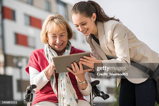 granddaughter and her grandmother looking at digital tablet - oma rollator stockfoto's en -beelden