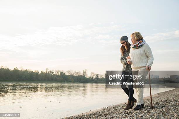 young woman assisting her grandmother walking - two generation family photos et images de collection