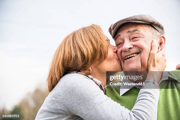 Adult daughter kissing father's cheek