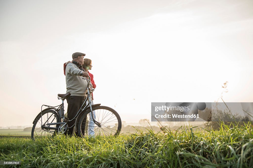 Senior man and daughter in rural landscape with bicycle