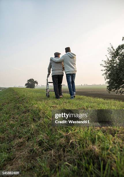 senior man and grandson in rural landscape with wheeled walker - arm around back stock pictures, royalty-free photos & images