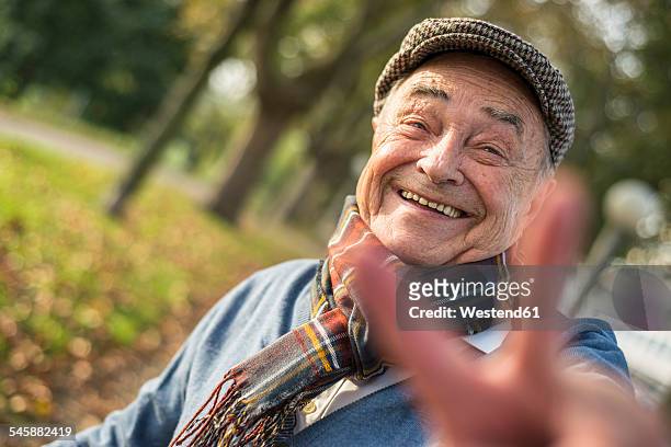 portrait of happy senior man outdoors doing victory sign - rentner mann allein lustig stock-fotos und bilder