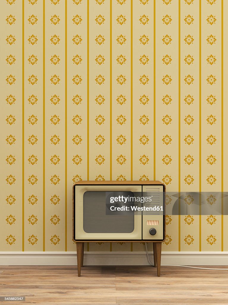 Old television in front of yellow patterned wallpaper