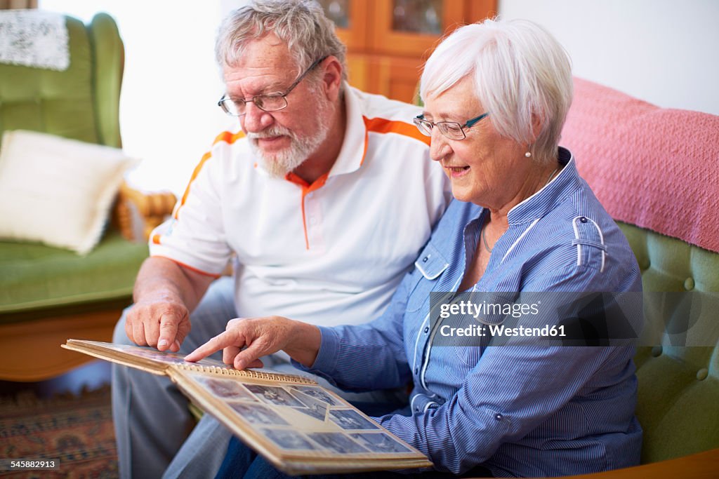 Senior couple at home looking at photo album