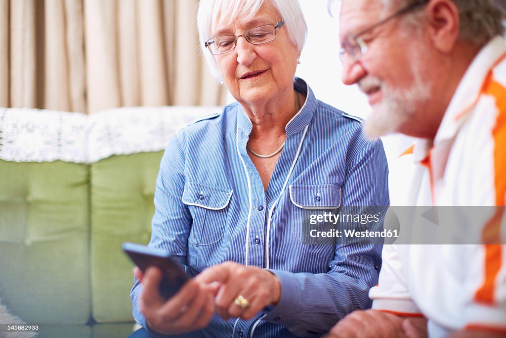 Senior couple with smart phone at home