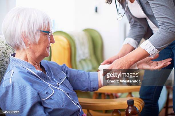 medic caring for senior woman at home - applying bandage stock pictures, royalty-free photos & images
