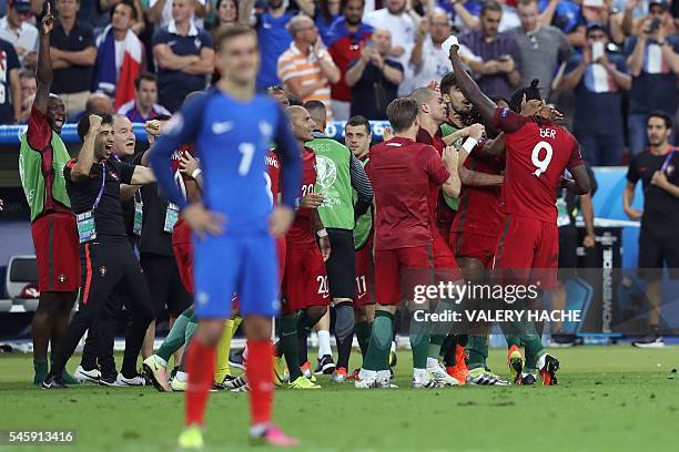 France's forward Antoine Griezmann looks on as Portugal's forward Eder celebrates with teammates after scoring a goal during the Euro 2016 final...