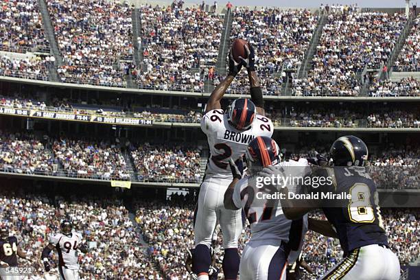 Eric Brown of the Denver Broncos leaps to catch the ball over Jeff Graham of the San Diego Chargers and teammate Denard Walker during the game at...