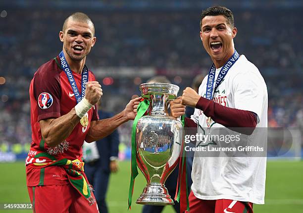 Cristiano Ronaldo and Pepe of Portugal pose for photographs holding the Henri Delaunay trophy to celebrate after their 1-0 win against France in the...