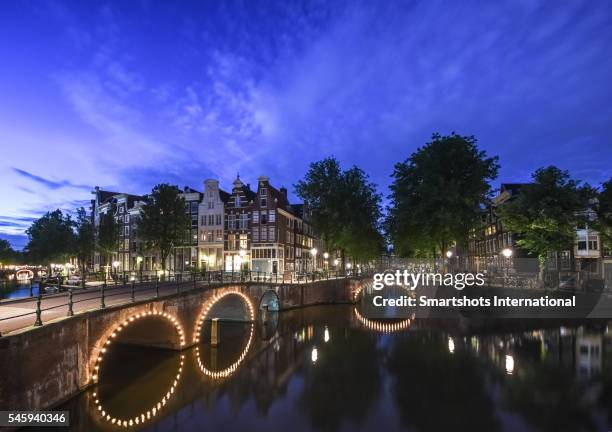 beautiful dutch bridges illuminated at dusk with reflection in central amsterdam, netherlands - canal disney stock pictures, royalty-free photos & images